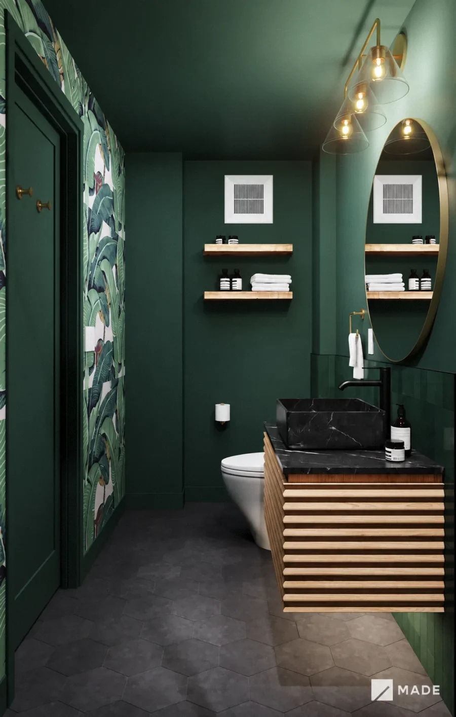 Deep green bathroom with patterned wallpaper, a brass mirror and a slatted wood vanity.